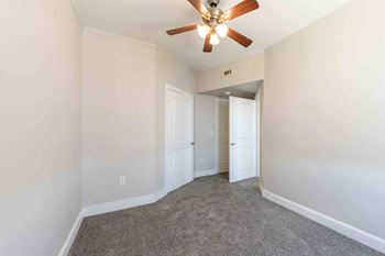 A room with a ceiling fan and carpeted floor.